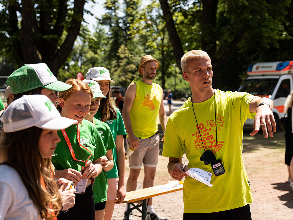 Ein Helfer zeigt Teilnehmenden den Weg.