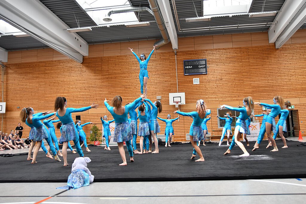 Eine Showgruppe in blauen Kostümen zeigt eine Choreographie mit Hebefigur.