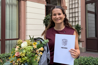Paula Gremm hält eine Urkunde und einen Blumenstrauß in den Händen.