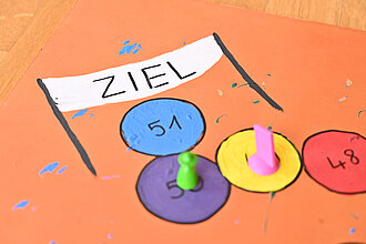 Zwei Hütchen stehen auf einem Spielbrett.