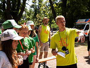 Ein Helfer zeigt Teilnehmenden den Weg.