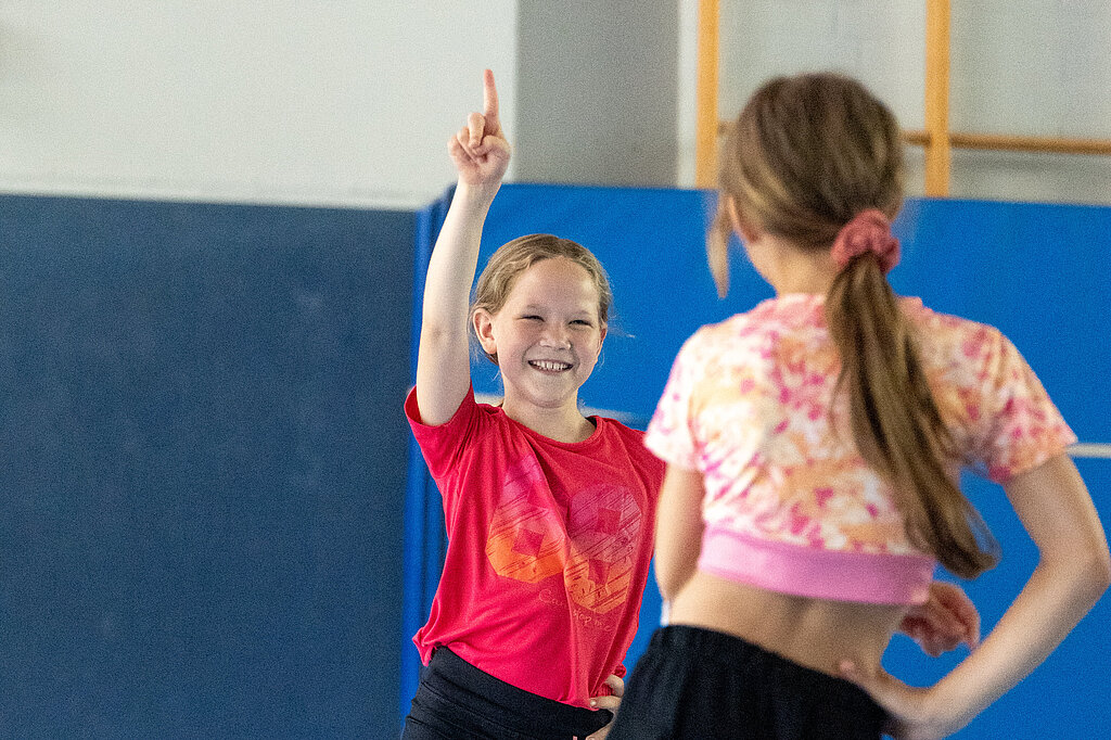 Zwei Mädchen tanzen zusammen in der Turnhalle.